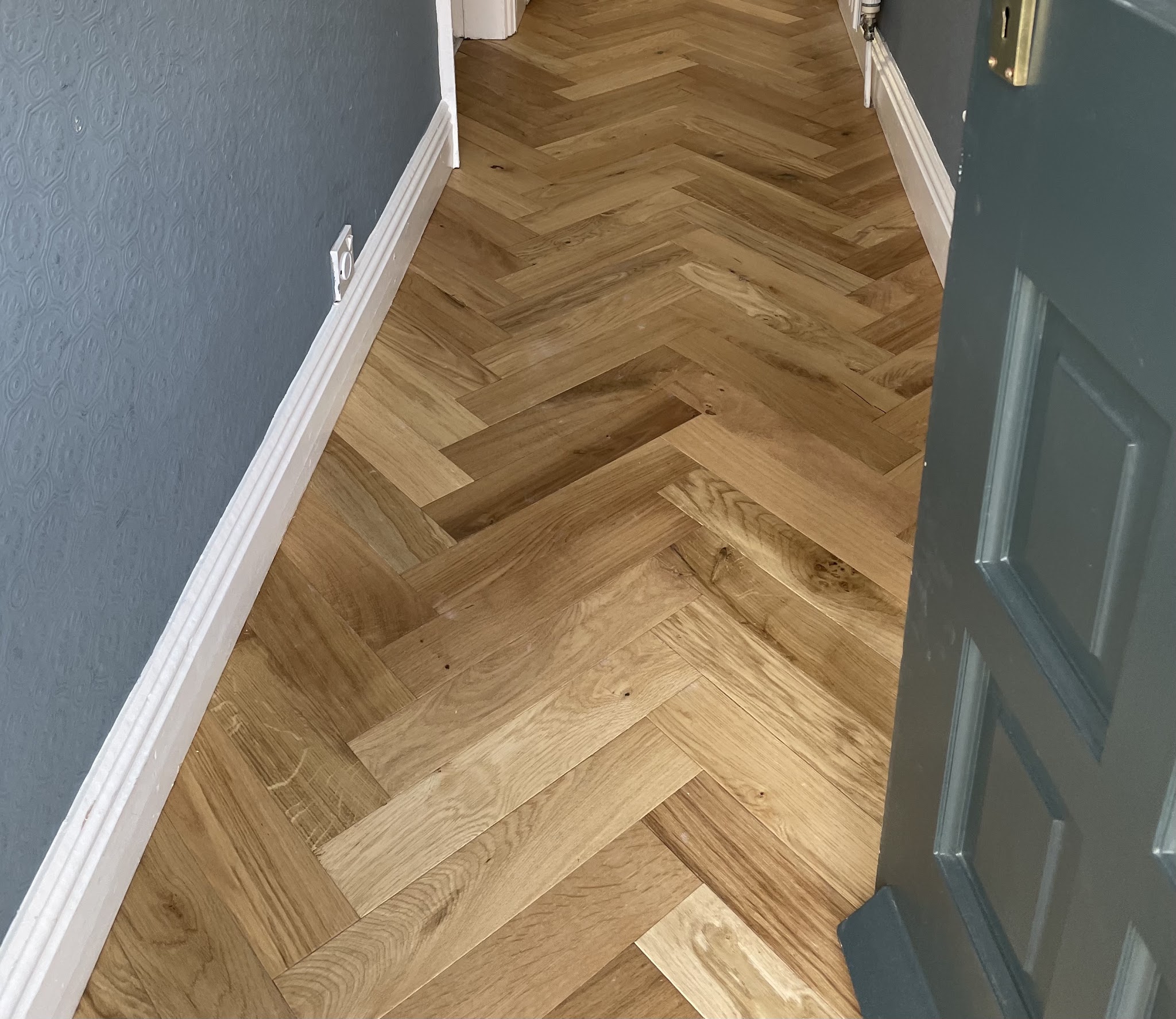 Beautifully fitted patterned flooring beside a dark green door